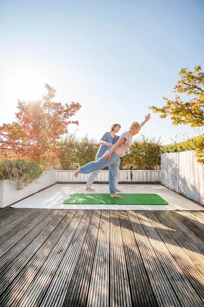 Rückenglück Personal Training im Freien – Trainerin korrigiert Balance-Übung auf Terrasse