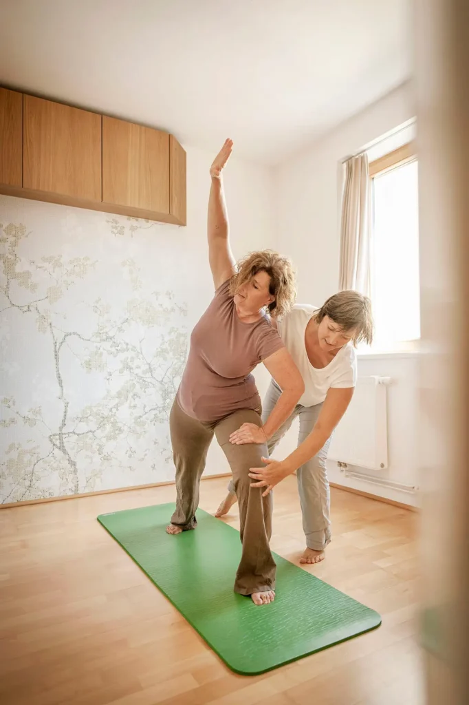 Trainerin unterstützt Kundin bei Seitdehnung im Rückenglück Personal Training Wien