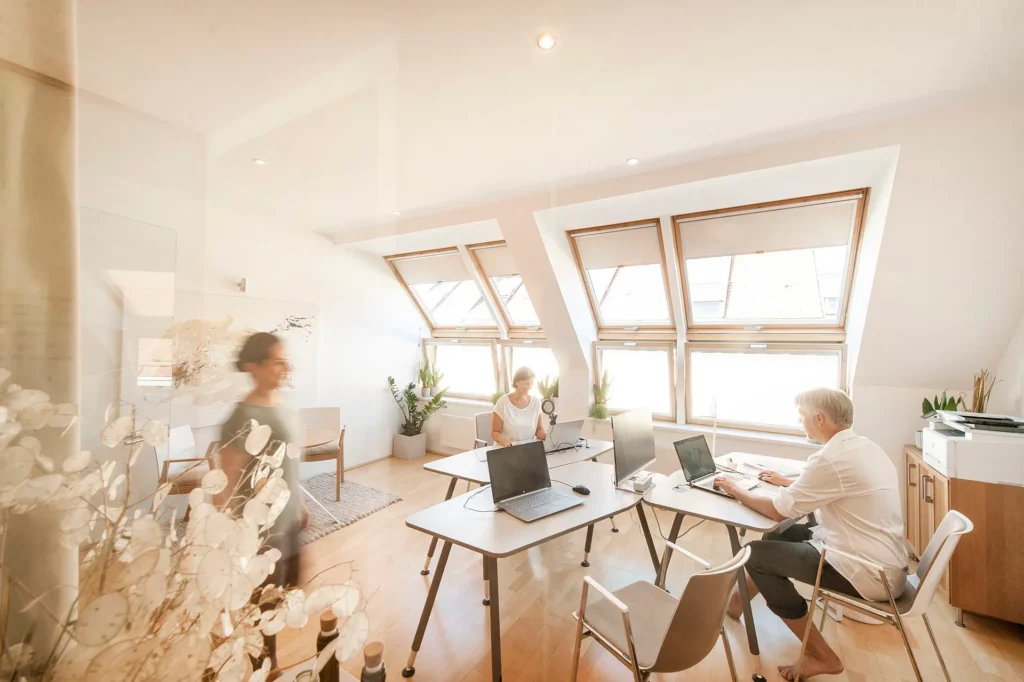 Helles Büro des Rückenglück Instituts Wien im Dachgeschoss mit Dachfenstern, Pflanzen und arbeitendem Team
